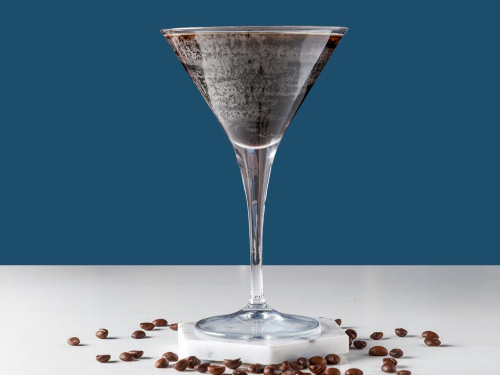 Espresso martini med kaffebønner på bord.