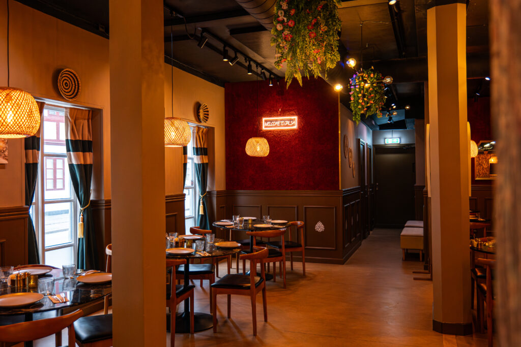 Moderne restaurantinteriør med dækkede borde og belysning.